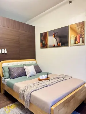 a bedroom with a bed with a wooden headboard at The Scandi Hub at Air Residences, Makati in Manila