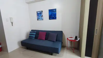 a blue couch with colorful pillows in a room at Shore Residences - 1BR Breezy Home Near the Sea in Manila