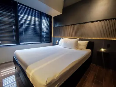 a large bed with white sheets in a room with windows at The Auberge at Air Residences Makati! in Manila