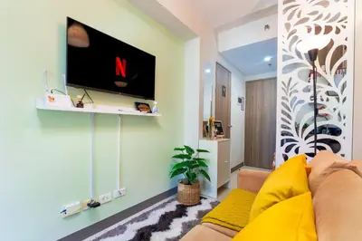 a living room with a couch and a tv on a wall at 1BR Staycation at S Residences Tower 1 in Manila