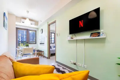 a living room with a couch and a tv on a wall at 1BR Staycation at S Residences Tower 1 in Manila