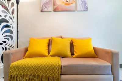 a couch with four yellow pillows on it at 1BR Staycation at S Residences Tower 1 in Manila