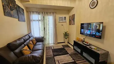 a living room with a couch and a flat screen tv at The Radiance Manila Bay Staycation by SonPai in Manila