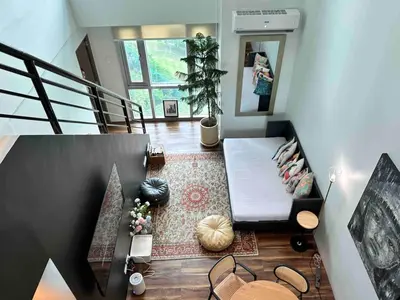 a room with a staircase with a couch and a table at Huge 101-SQM 2BR in Central BGC Up to 12 Guests in Manila