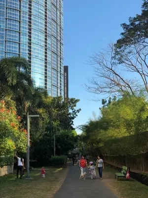a group of people walking in a park with a tall building at Huge 101-SQM 2BR in Central BGC Up to 12 Guests in Manila