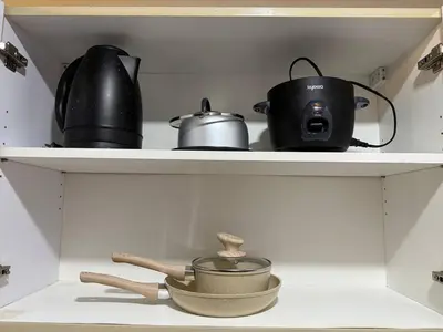 a shelf with pots and pans and a tea pot at Iris Affordable and Neat Staycation at Air Residences Makati in Manila