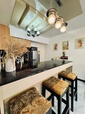 a kitchen with a bar with two stools at Avida Towers San Lazaro in Manila