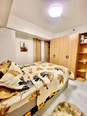a bedroom with a bed with a floral comforter at Avida Towers San Lazaro in Manila