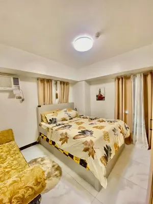 a bedroom with a bed and a chair at Avida Towers San Lazaro in Manila