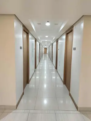 a corridor in a building with white floors and wooden doors at Chino Roces Makati - No Parking - Red Residences in Manila