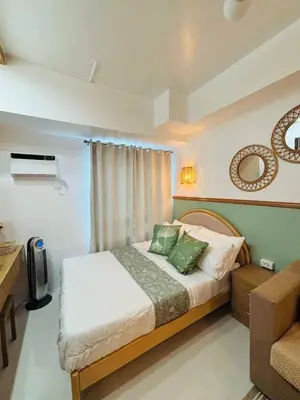 a bedroom with a large bed with green pillows at Grand View Tower - Metro Stay in Manila