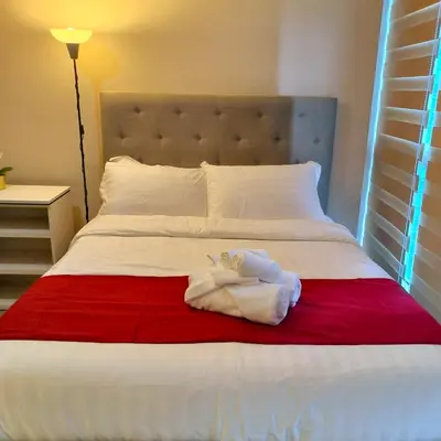 a white bed with a red and white blanket at Cozy Modernistic 1 BR Uptown BGC in Manila