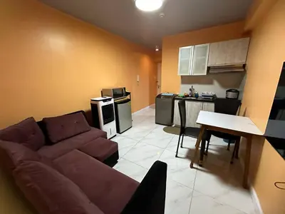 a living room with a couch and a kitchen at Cozy-AIS Staycation in Manila