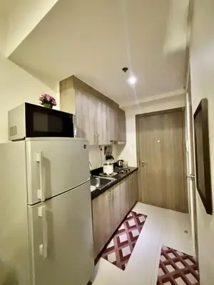a kitchen with a white refrigerator and wooden cabinets at Your Skyline Hideaway in Manila