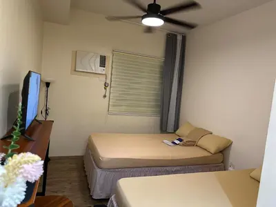 a small room with two beds and a ceiling fan at SplashNStay 18sqm condi near AUP,PNPA CKS College Sta Rosa Tagaytay road Silang Cavite in Puting Kahoy
