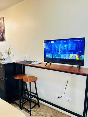 a television on a counter with two stools at SplashNStay 18sqm condi near AUP,PNPA CKS College Sta Rosa Tagaytay road Silang Cavite in Puting Kahoy