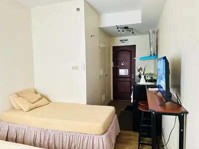 a bedroom with a bed and a desk with a computer at SplashNStay 18sqm condi near AUP,PNPA CKS College Sta Rosa Tagaytay road Silang Cavite in Puting Kahoy