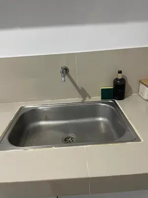 a stainless steel sink in a white kitchen at Cozy Hideout-Free Parking, Netflix & Arcade Games in Cainta