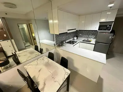 a kitchen with white cabinets and a table and chairs at Family room Staycation Near MOA in Manila
