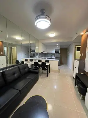 a large living room with a black couch and chairs at Family room Staycation Near MOA in Manila