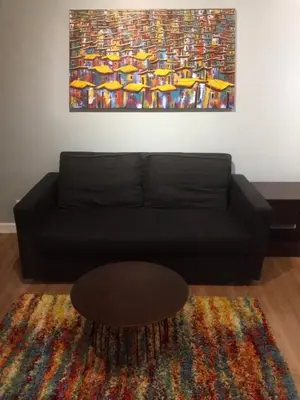 a black couch in a living room with a painting at Two Maridien 41stFlr Studio -Minimalist Functional in Manila