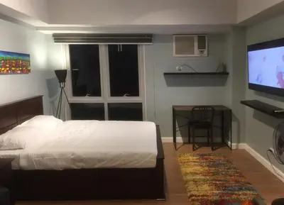 a bedroom with a bed and a flat screen tv at Two Maridien 41stFlr Studio -Minimalist Functional in Manila