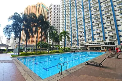 a large swimming pool in front of tall buildings at A Comfy Self-Check-In and Check-out 1BR Light Residences in Manila