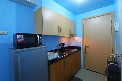 a kitchen with a sink and a tv on top of a refrigerator at A Comfy Self-Check-In and Check-out 1BR Light Residences in Manila