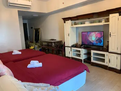 a living room with two beds and a flat screen tv at 81NB Cozy Studio -City View, 2 Queen Beds, NAIA T3 in Manila