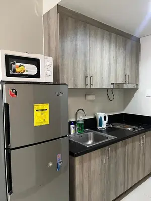 a kitchen with a microwave on top of a refrigerator at 1 bedroom condo unit near MOA in Manila