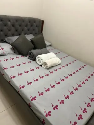 a bed with a white blanket with flowers on it at 1 bedroom condo unit near MOA in Manila