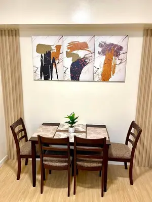 a dining room table with four chairs and a painting at Cityscape Stays in Manila