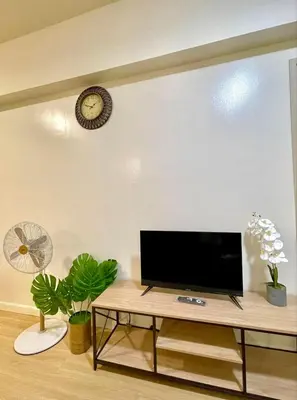 a living room with a tv and a clock on the wall at Cityscape Stays in Manila