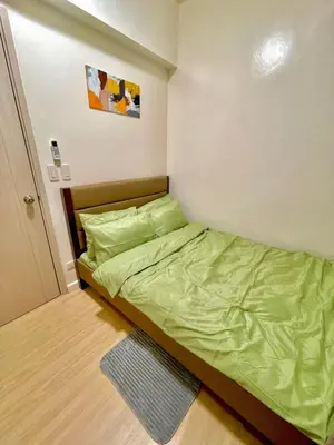 a small bedroom with a bed with green sheets at Cityscape Stays in Manila