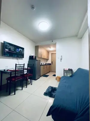a room with a bed and a table and a kitchen at Minimalist Flat Retreat- Shore Residences in Manila