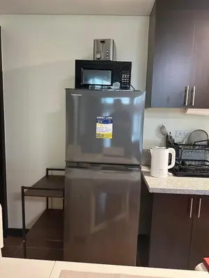 a microwave sitting on top of a refrigerator in a kitchen at 2BR Condo in Makati- Good for 6! in Manila