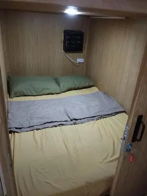 a small bed in a small room with a door at Capsule park avenue in Manila