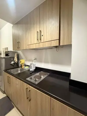 a kitchen with a sink and wooden cabinets at Shore Residences 1BR Staycation in Manila
