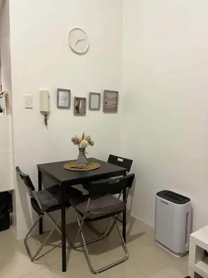 a dining room table with chairs and a clock on the wall at Shore Residences 1BR Staycation in Manila