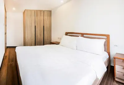 a bedroom with a large white bed and a wooden cabinet at Grand Marina Residences in Manila