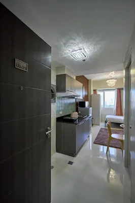 a kitchen with wooden cabinets and a refrigerator at Vista Blooms Stay at Vista Shaw with WiFi in Manila