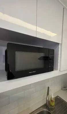 a microwave above a sink in a kitchen at Center of BGC- Your Home In Forbeswood Parklane in Manila
