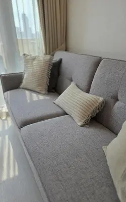 a gray couch with pillows sitting in a living room at Center of BGC- Your Home In Forbeswood Parklane in Manila