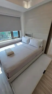 a large bed in a room with a window at Center of BGC- Your Home In Forbeswood Parklane in Manila