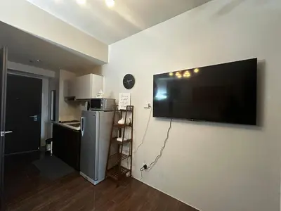 a living room with a large flat screen tv on a wall at MySunset at Air Residences Makati in Manila