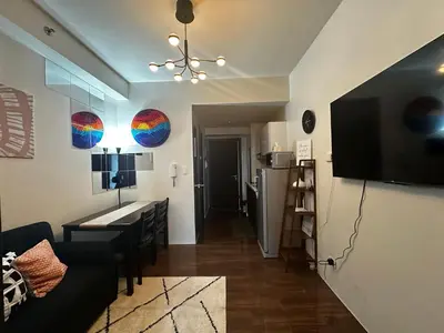 a living room with a couch and a table and a refrigerator at MySunset at Air Residences Makati in Manila