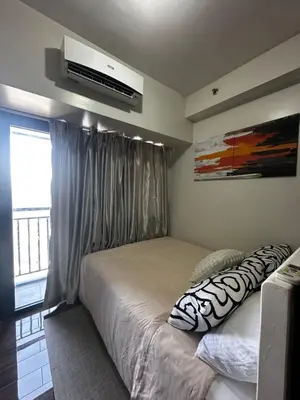 a bedroom with a bed and a television on the wall at MySunset at Air Residences Makati in Manila