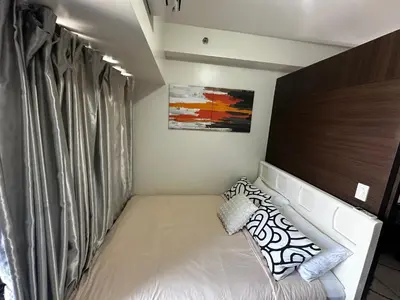 a small bedroom with a bed and a curtain at MySunset at Air Residences Makati in Manila