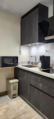 a kitchen with black cabinets and a sink at 29c BGC Cozy Suite Steps Away From Major Malls with Paid Parking and Gym with Fast Wi-fi in Manila