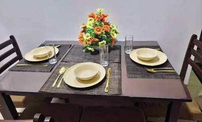 a table with two plates and a vase of flowers at Colin's Suite - Hope Residences, Trece Martires in Trece Martires